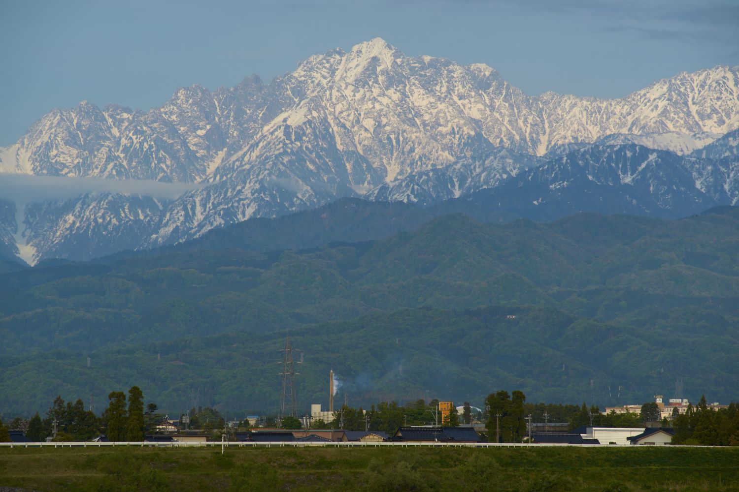 Deep within the lush green hills, Mount Tsurugi stands towering, its slopes still clinging to lingering snow.