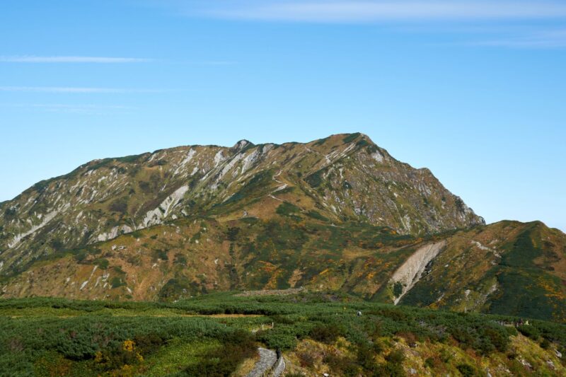 Against the blue sky, the slopes of Mount Okudainichi spread with a mottled pattern of autumn leaves and greenery.