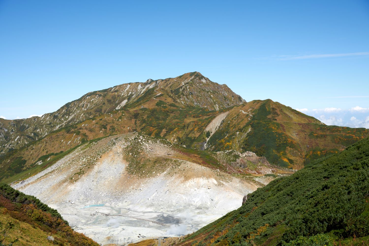 Against the backdrop of Mount Ōdainichi, the view below reveals the expanse of Mt. Tateyama Jigokudani, with its white rock faces and rising fumaroles.