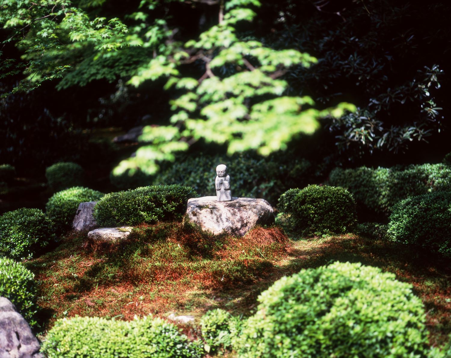 A photograph of a small Jizō statue in the moss garden of Sanzen-in Temple in Ōhara.