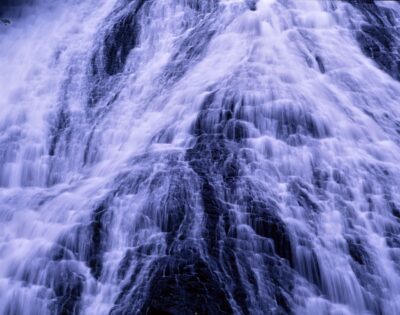 Close-up shot of Yudaki Falls in Oku-Nikkō. The powerful sight of white water cascading down, splitting into multiple streams as it covers the black rock face.