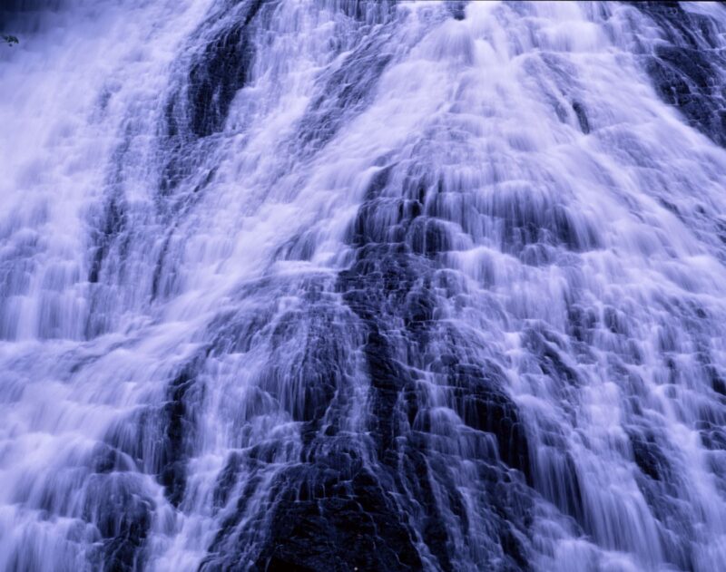 Close-up shot of Yudaki Falls in Oku-Nikkō. The powerful sight of white water cascading down, splitting into multiple streams as it covers the black rock face.