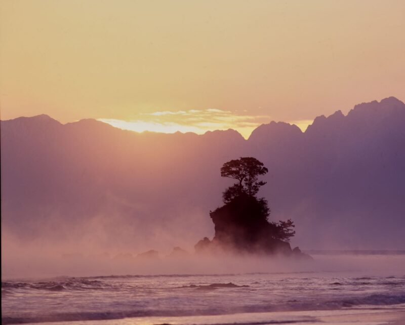 The purple sky before dawn and the misty rain enveloping the Onna-iwa rock at Amahare Beach.