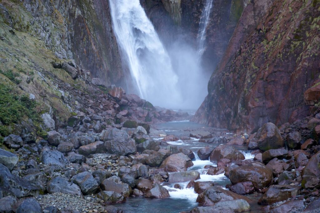 Near the base of Shōmyō Falls. Water spray dances in the air, and light reflecting off the rock face glows mysteriously.