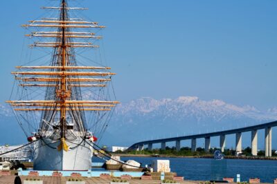 A full view of the Kaiō Maru, photographed head-on with Mt. Tateyama and the Shinminato Bridge in the background.
