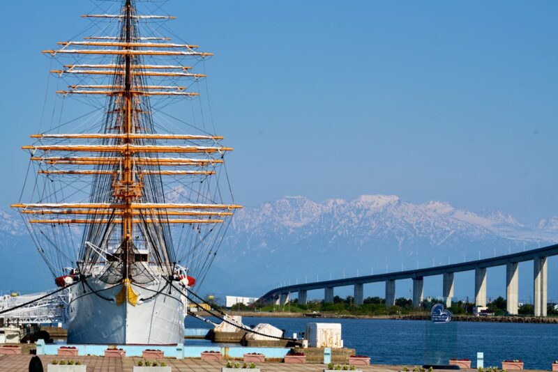 A full view of the Kaiō Maru, photographed head-on with Mt. Tateyama and the Shinminato Bridge in the background.