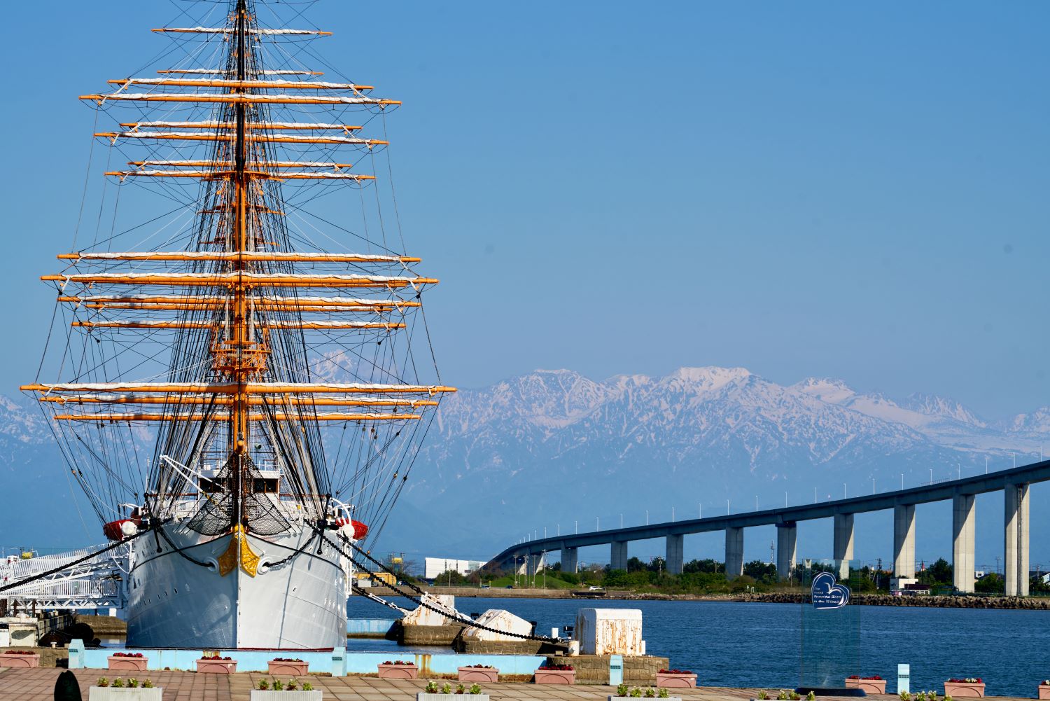 A full view of the Kaiō Maru, photographed head-on with Mt. Tateyama and the Shinminato Bridge in the background.