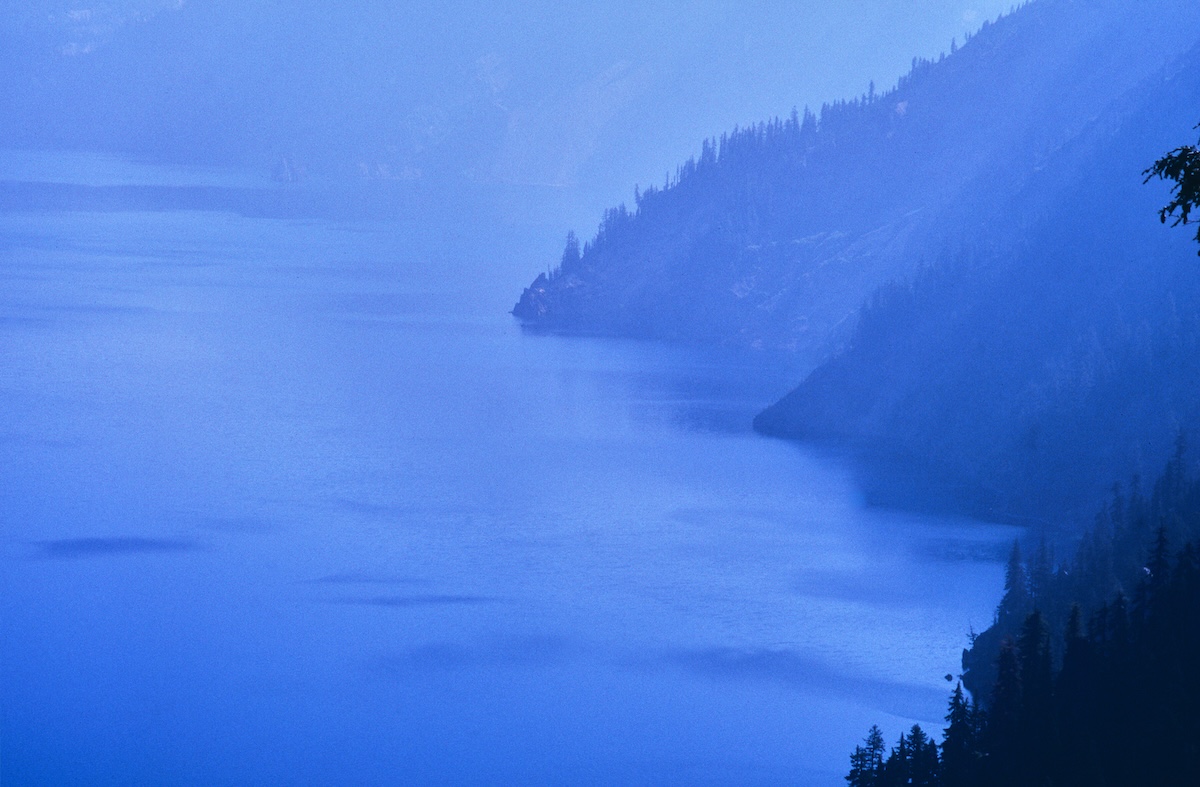 The blue lake surface and rock face seen from the cliffs of Crater Lake