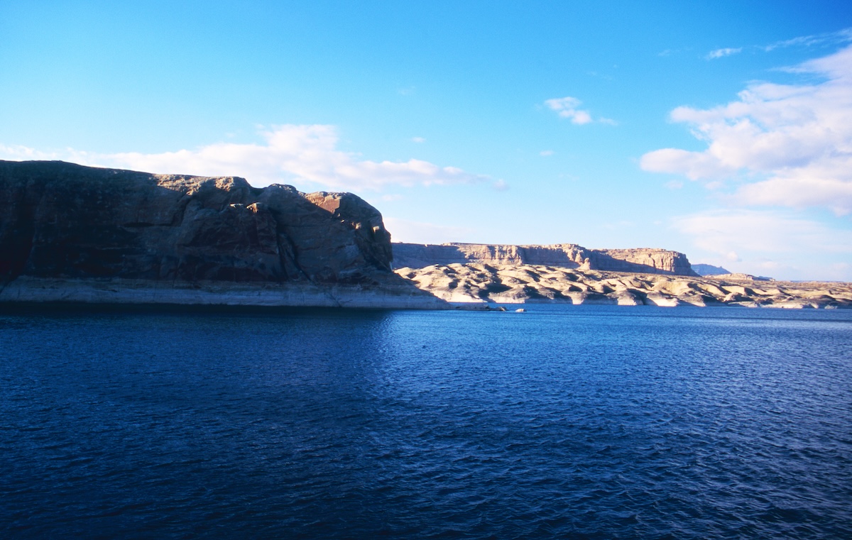 The blue surface of Lake Powell and the rock walls illuminated by the afternoon sun