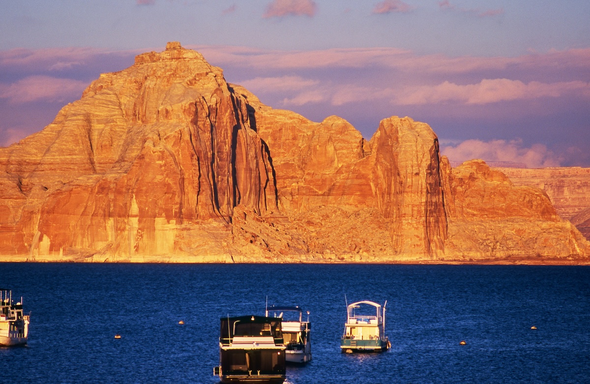 Lake Powell's surface and rock walls bathed in the pale light after sunset