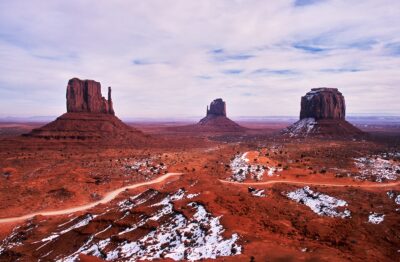 Monument Valley in winter. A grand panorama of buttes lining the landscape, with snow lingering on the red desert.
